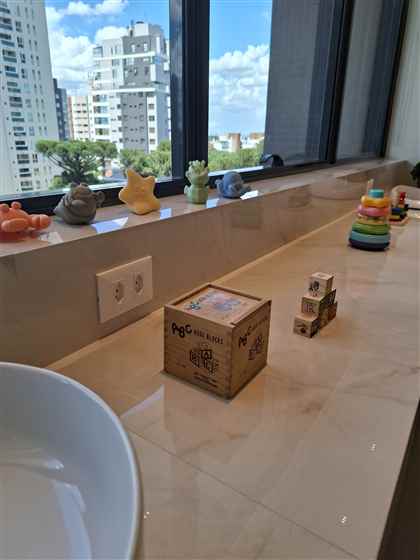 Brinquedos e mordedores de bebê na janela do consultório, com vista para Curitiba